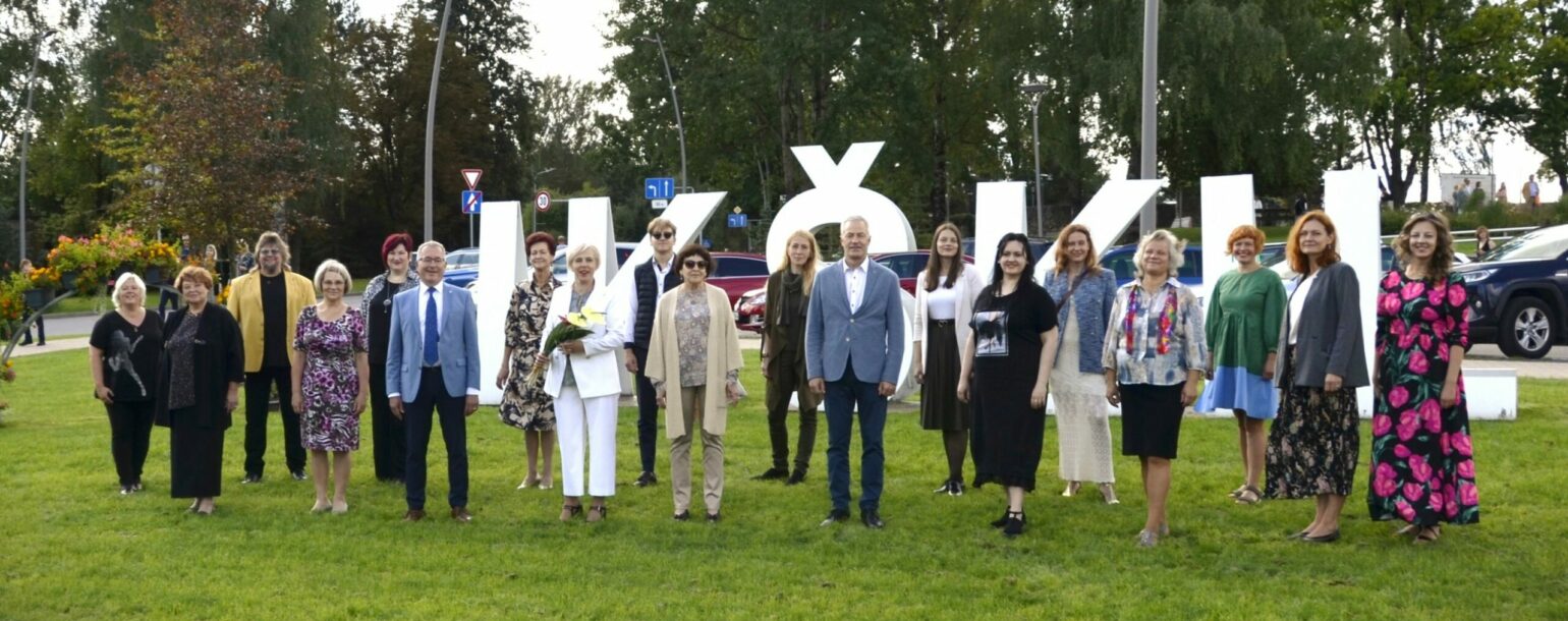 Cilvēki stāv pie burtiem